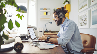 a man wearing headphones and sitting at a desk with a laptop