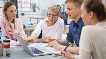 A group of people looking at a laptop.